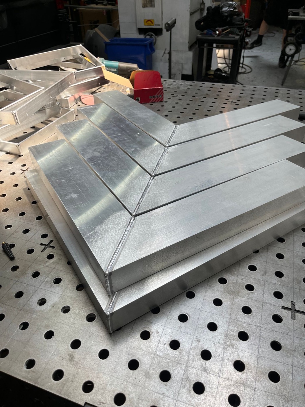 Stack of welded aluminum frames with mitered corners on a welding table